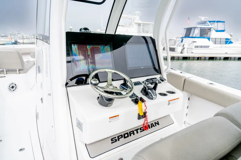 Slide: The Image of 2021 Sportsman Open 322 Center Console boat dashboard with steering wheel and navigation screens. - 5