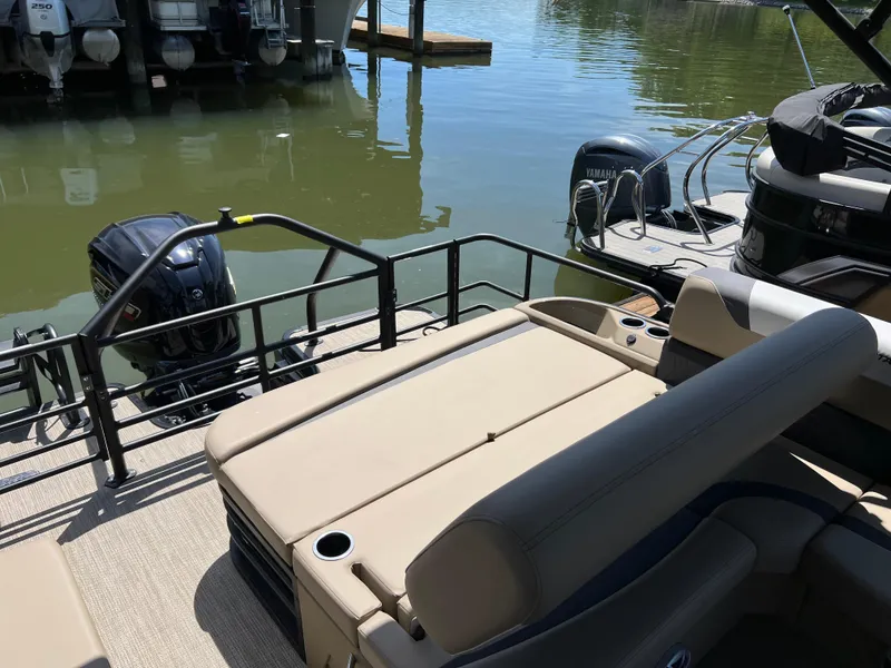 Slide: The Image of 2025 Starcraft SLS 3 Q DH pontoon boat with beige seating, docked by the water. - 19