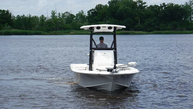 Slide: The Image of 2024 Sea Pro 230 Bay boat navigating a calm river with lush greenery in the background. - 1