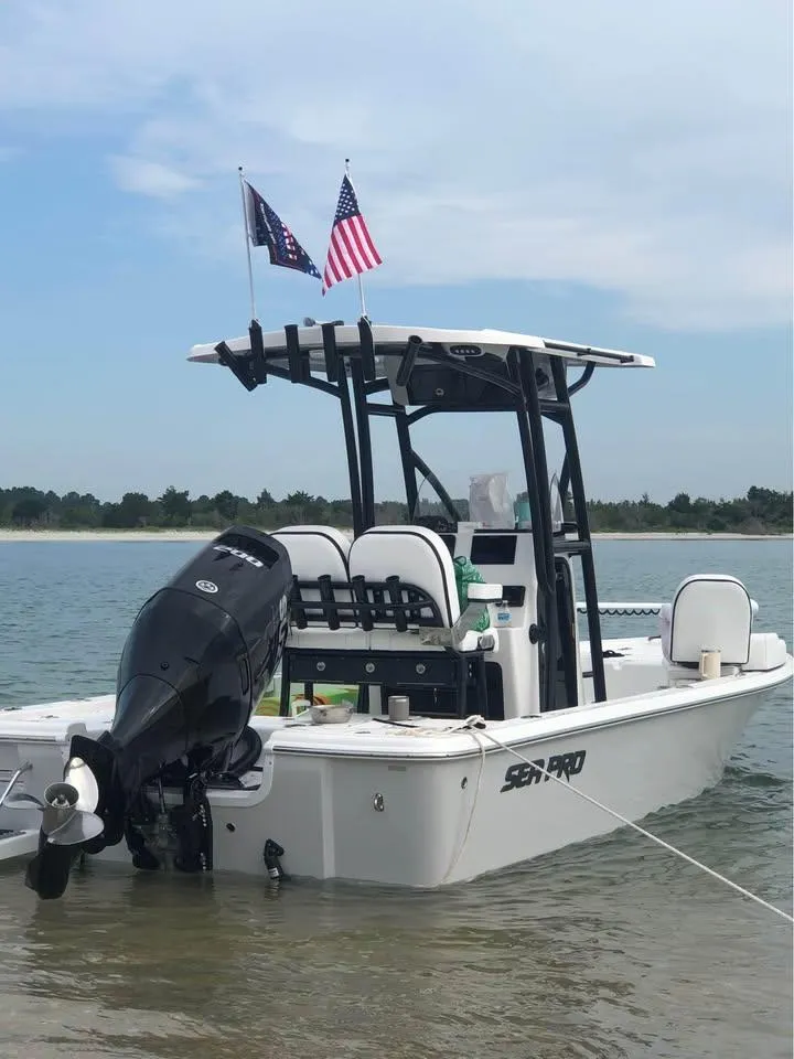Slide: The Image of 2024 Sea Pro 230 Bay boat anchored in shallow water with flags on the T-top. - 19