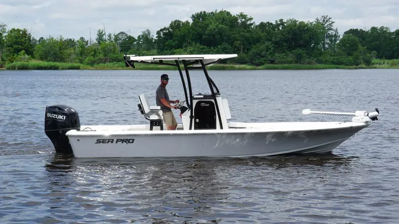Slide: The Image of 2024 Sea Pro 230 Bay boat on water, featuring Suzuki outboard motor, with lush greenery in background. - 3