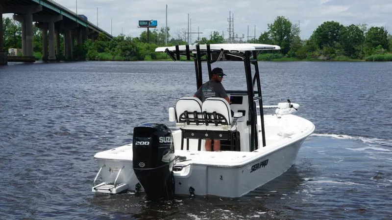 Slide: The Image of 2024 Sea Pro 230 Bay boat on water with Suzuki engine, bridge in background. - 5