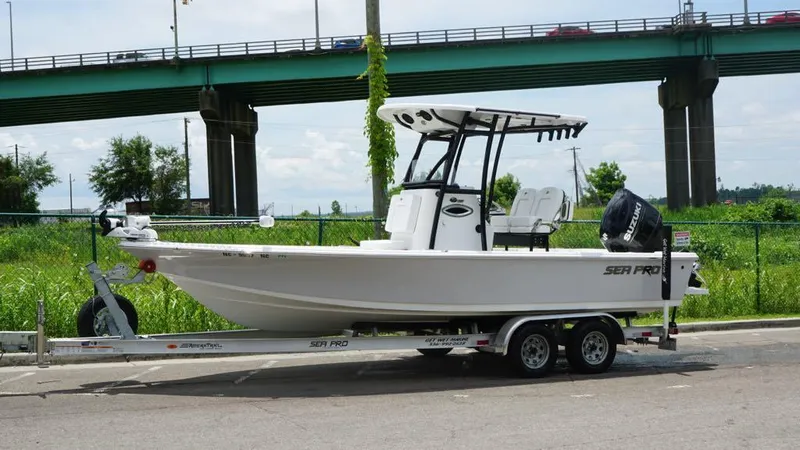 Slide: The Image of 2024 Sea Pro 230 Bay boat on trailer, parked near a bridge. - 7