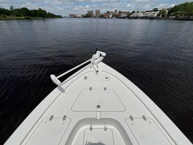 Slide: The Image of 2024 Sea Pro 230 Bay boat on calm river with cityscape in background. - 9