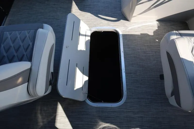 Slide: The Image of 2021 Bennington 24 RTFB boat interior with open storage compartment between seats. - 10
