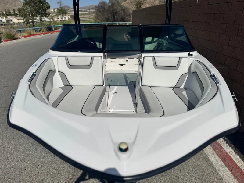 Slide: The Image of 2018 Yamaha AR190 boat with sleek white interior and windshield, parked on a sunny road. - 10