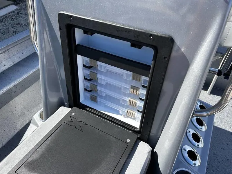 Slide: The Image of 2025 Xpress H20B boat storage compartment with tackle boxes and rod holders. - 14
