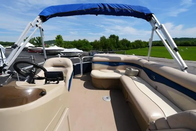 Slide: The Image of 2012 Bennington 24 SLX pontoon boat with spacious seating and blue canopy on a sunny day. - 11