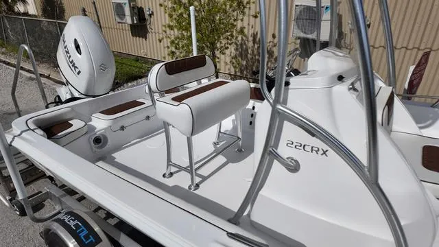 Slide: The Image of 2025 ALK2 22CRX boat interior with seating and motor, parked outdoors. - 13