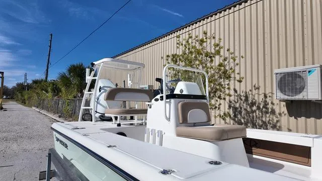 Slide: The Image of 2025 Spyder Boats FX19 Vapor, sleek design, parked outdoors near a metal building. - 36