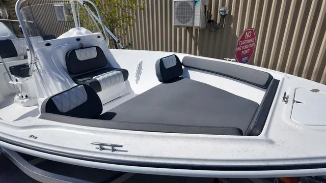 Slide: The Image of 2025 ALK2 18CRS boat with cushioned seating and sleek design, docked near a building. - 11