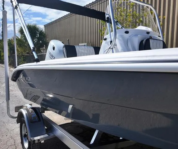 Slide: The Image of 2025 ALK2 18CRS boat on trailer with Suzuki engine, parked outdoors. - 18