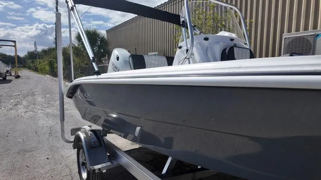 Slide: The Image of 2025 ALK2 18CRS boat on trailer, parked outdoors near industrial building. - 43