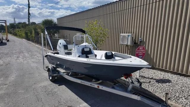 Slide: The Image of 2025 ALK2 18CRS boat on trailer, parked outdoors near a corrugated metal building. - 46
