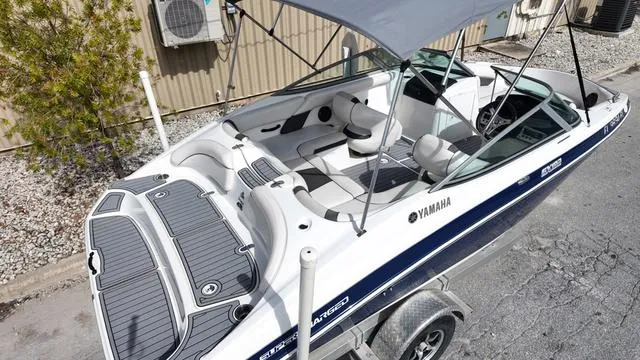 Slide: The Image of 2013 Yamaha Boats SX192 with canopy, parked on trailer, featuring sleek design and spacious seating. - 11