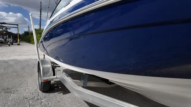 Slide: The Image of 2013 Yamaha Boats SX192 on trailer, blue hull, parked on gravel. - 13