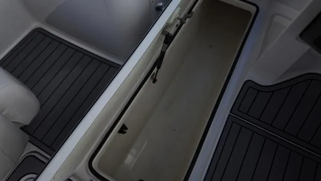 Slide: The Image of 2013 Yamaha Boats SX192 storage compartment with black flooring. - 16