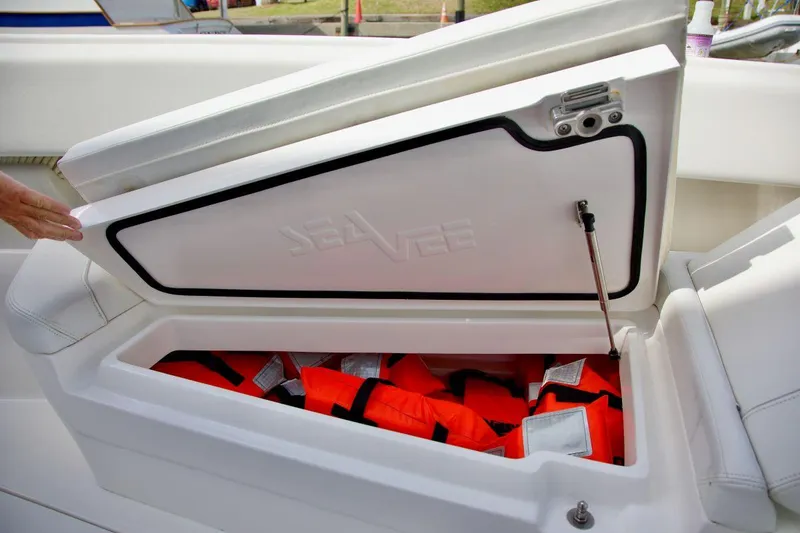 Slide: The Image of Open storage compartment on 2024 SeaVee 390Z boat, containing orange life jackets. - 19