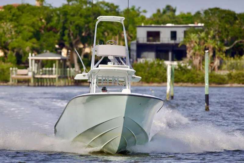 Slide: The Image of 2024 SeaVee 390Z boat cruising on water, surrounded by lush greenery. - 2