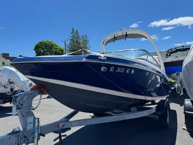 Slide: The Image of 2021 Yamaha Boats 195S on trailer, sleek design, blue hull, sunny day. - 1