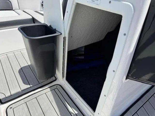 Slide: The Image of 2021 Yamaha Boats 195S interior storage compartment with trash bin on deck. - 10