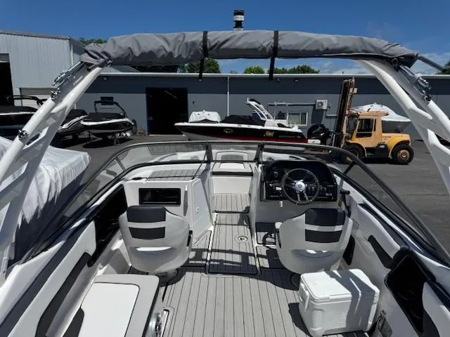 Slide: The Image of 2021 Yamaha Boats 195S interior with modern helm, seating, and sleek design in a marina setting. - 20