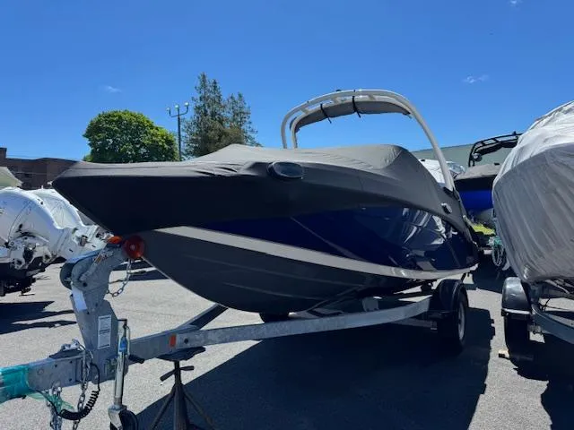 Slide: The Image of 2021 Yamaha Boats 195S on trailer, covered, parked outdoors under clear blue sky. - 3