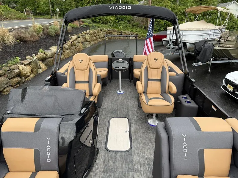 Slide: The Image of 2025 Viaggio X20U Tri-Toon boat with luxurious seating and American flag in a scenic setting. - 12