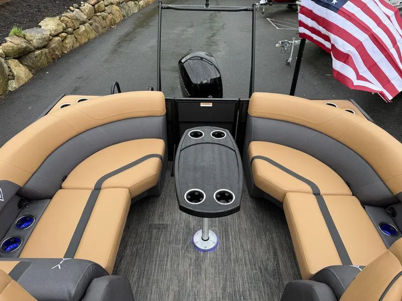 Slide: The Image of 2025 Viaggio X20U Tri-Toon boat interior with tan seating and table, American flag visible. - 13
