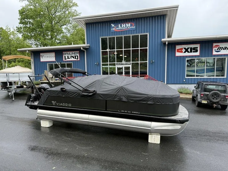 Slide: The Image of 2025 Viaggio X20U Tri-Toon boat with cover, parked outside dealership. - 15