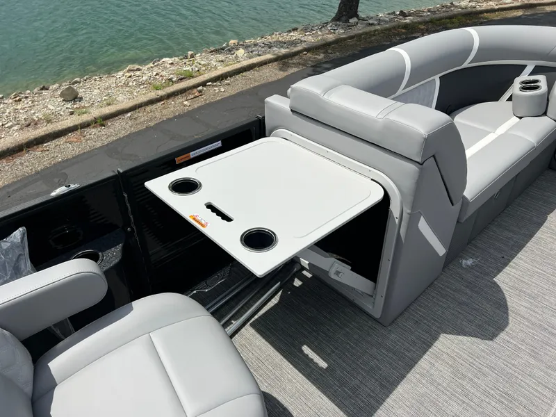 Slide: The Image of 2025 Crest Classic 220 SLRC boat interior with fold-out table and seating by the water. - 15