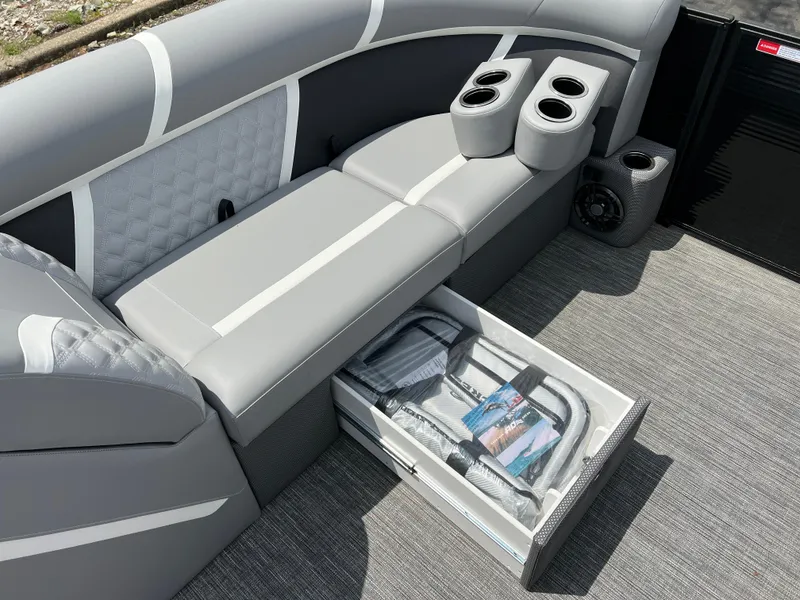 Slide: The Image of 2025 Crest Classic 220 SLRC boat interior with gray seating, cup holders, and storage drawer. - 17