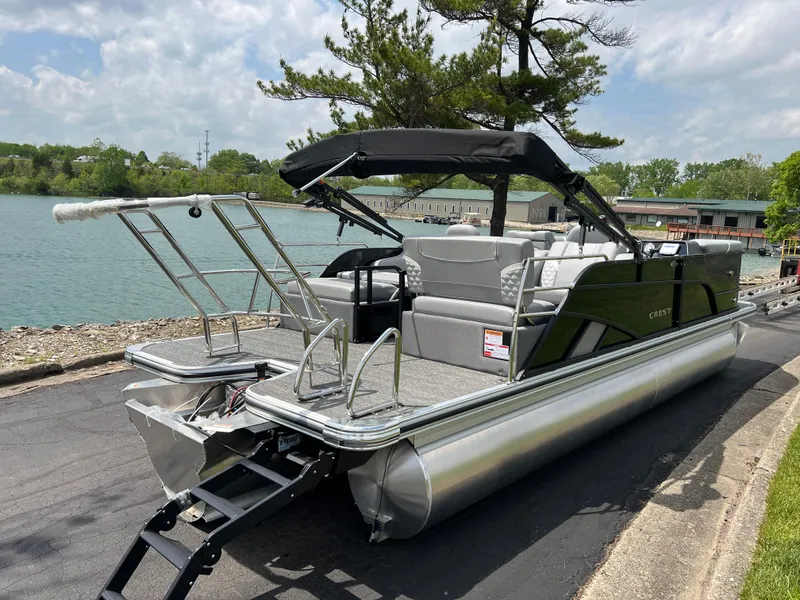 Slide: The Image of 2025 Crest Classic 220 SLRC pontoon boat docked by a scenic lakeside. - 5