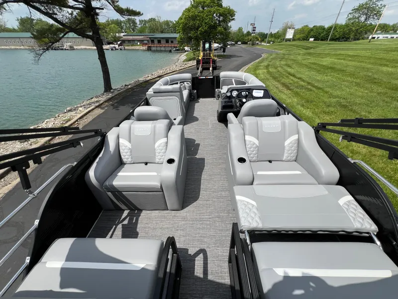 Slide: The Image of 2025 Crest Classic 220 SLRC pontoon boat with spacious seating by a lakeside. - 9