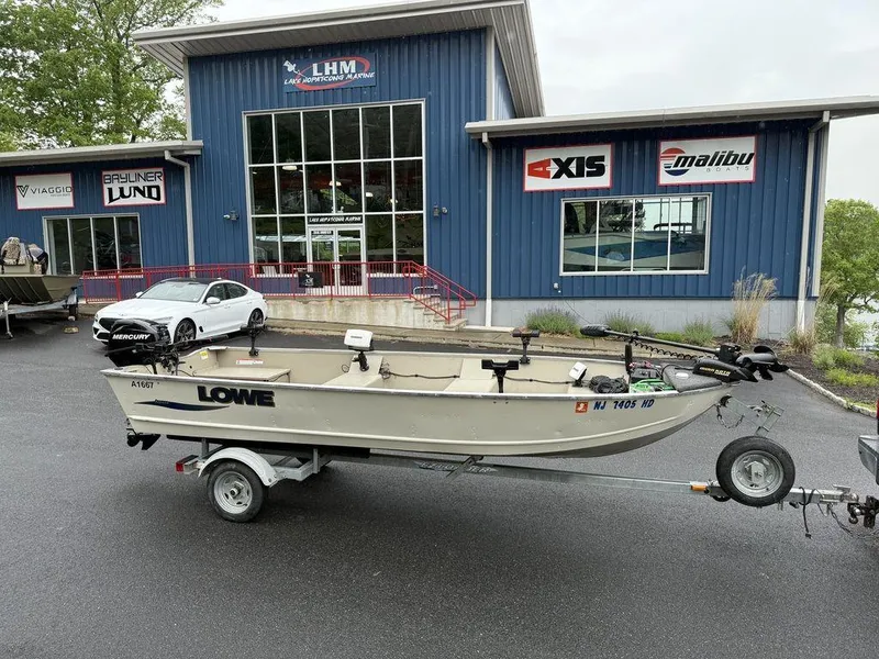 The Image of 2011 Lowe ANGLER A1667 boat on trailer outside dealership with blue building. - 1
