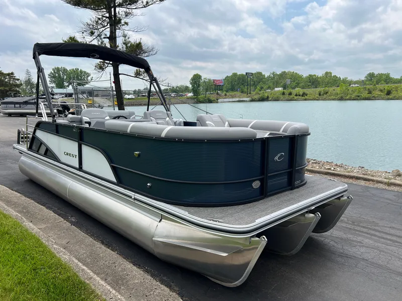 Slide: The Image of 2025 Crest Classic 220 SLRC pontoon boat docked by a serene lake. - 3