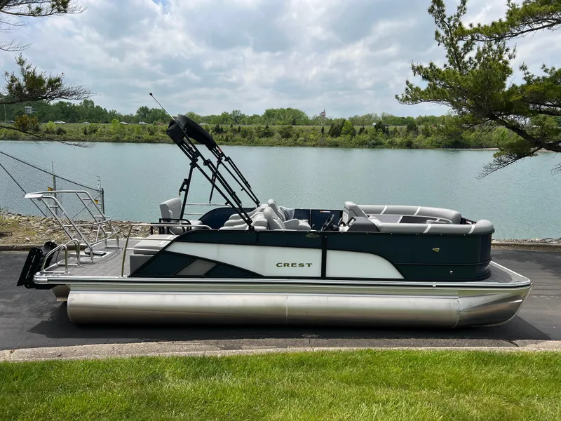Slide: The Image of 2025 Crest Classic 220 SLRC pontoon boat by a serene lake. - 4