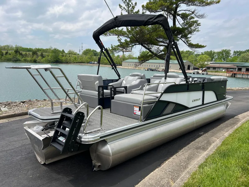 Slide: The Image of 2025 Crest Classic 220 SLRC pontoon boat docked by a serene lake. - 5