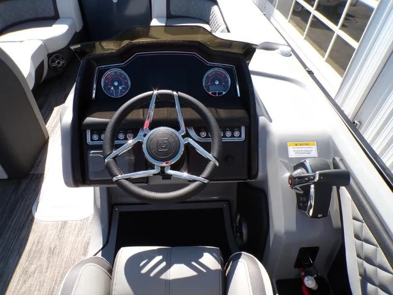 Slide: The Image of 2025 Godfrey AquaPatio 255 SFL boat dashboard with steering wheel and control panel. - 2