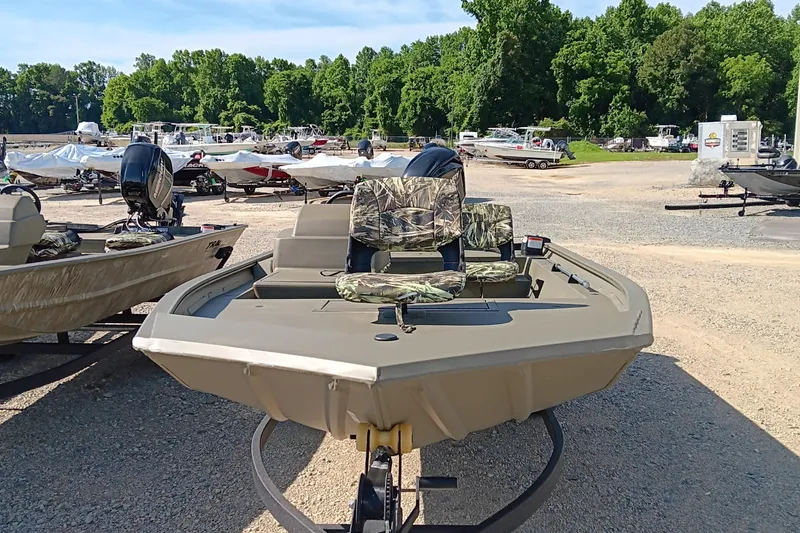 Slide: The Image of 2025 Tracker Grizzly 1754 SC boat in a marina, featuring camouflage seating. - 2