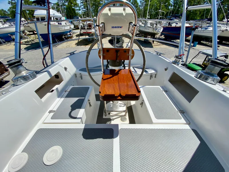 Slide: The Image of 1979 Valiant 37 sailboat cockpit with wooden seating and steering wheel, docked in a marina. - 17