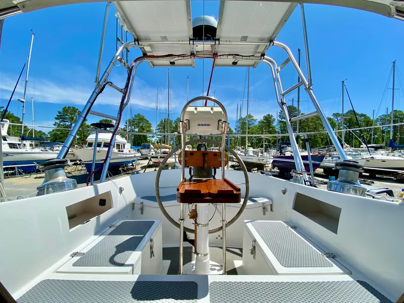 Slide: The Image of 1979 Valiant 37 sailboat cockpit with steering wheel, docked in a marina under clear blue sky. - 22