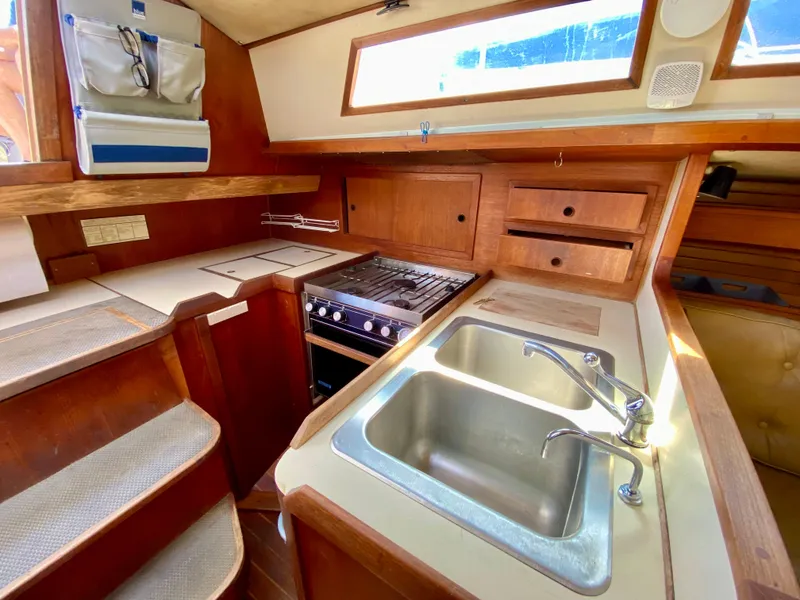 Slide: The Image of 1979 Valiant 37 yacht kitchen with wooden cabinetry, dual sink, and stove. - 25