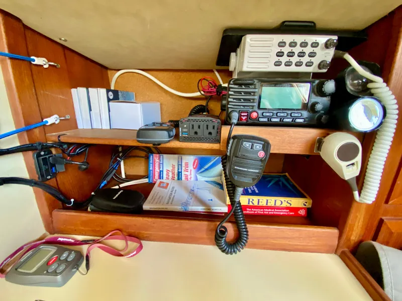 Slide: The Image of 1979 Valiant 37 navigation equipment with radios, manuals, and communication devices in wooden cabinet. - 27
