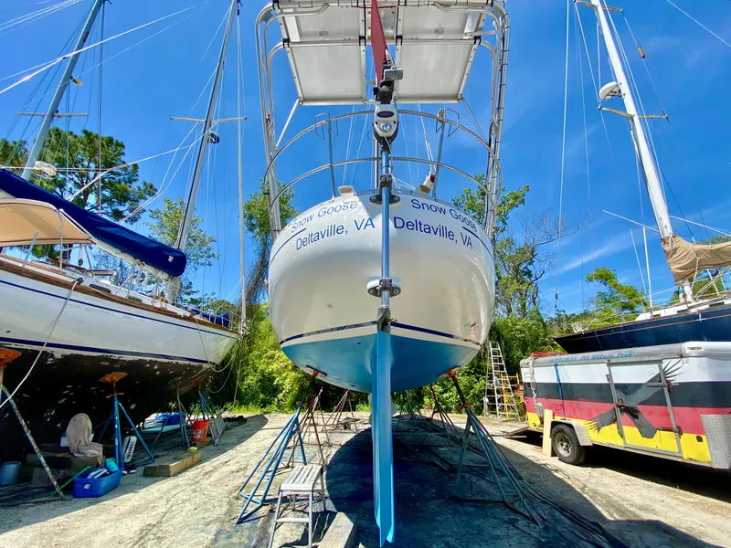 Slide: The Image of 1979 Valiant 37 sailboat on stands, surrounded by trees and other boats, under clear blue sky. - 3