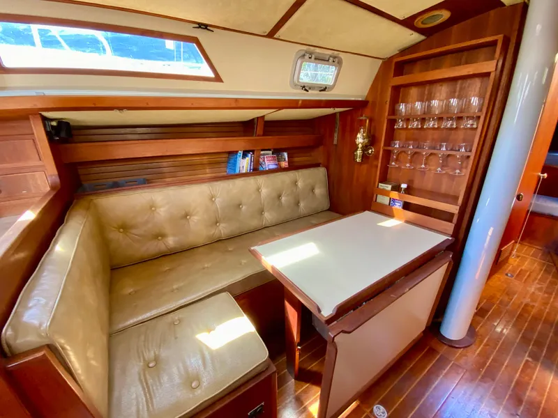 Slide: The Image of 1979 Valiant 37 yacht interior with cozy seating, wooden table, and glass storage. - 36
