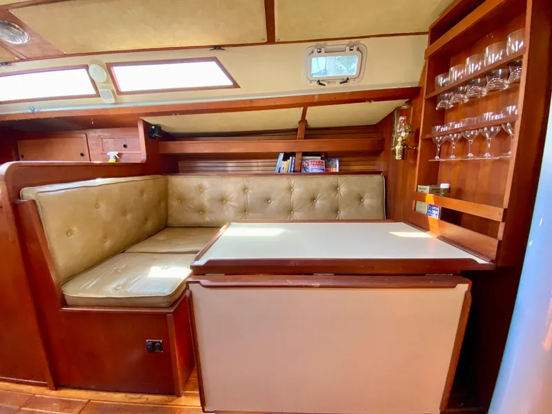 Slide: The Image of 1979 Valiant 37 yacht interior with dining area, cushioned seating, and built-in glass rack. - 37