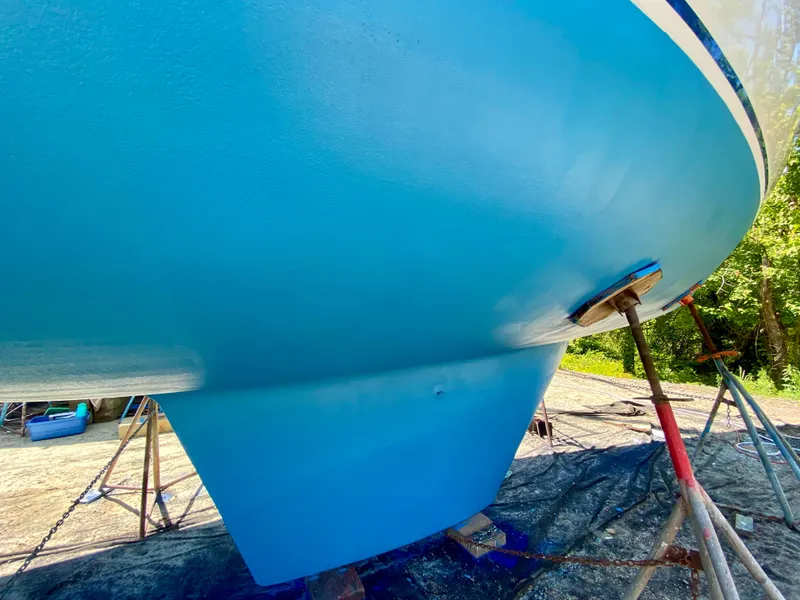 Slide: The Image of 1979 Valiant 37 sailboat hull in bright blue, supported on stands outdoors. - 7
