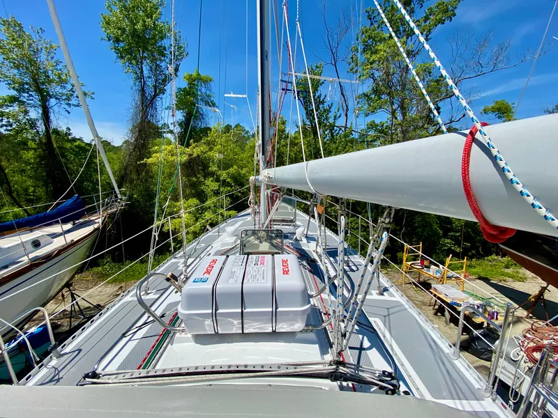 Slide: The Image of 1979 Valiant 37 sailboat deck with rigging and life raft, surrounded by trees. - 8