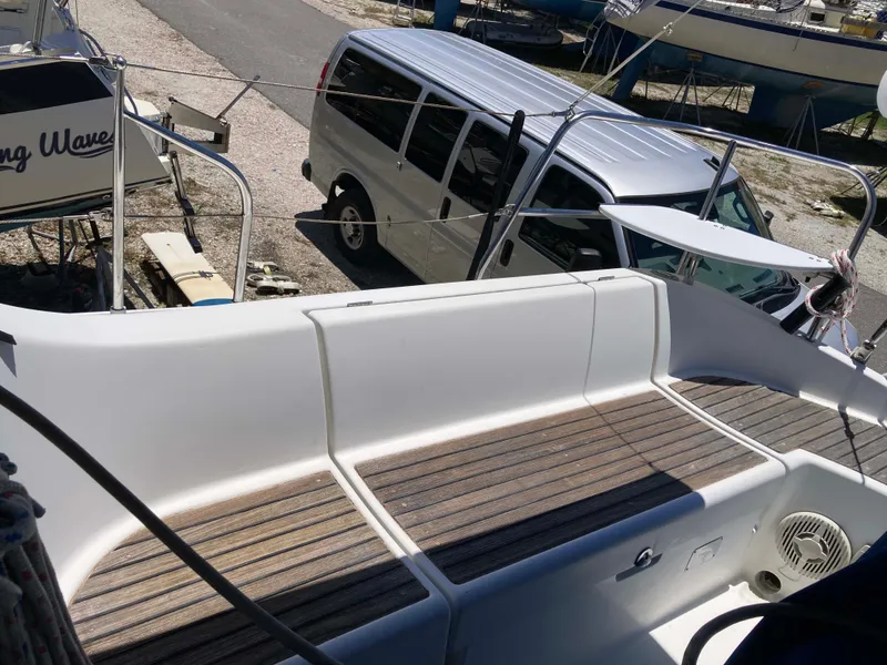 Slide: The Image of 1993 Beneteau Oceanis 370 sailboat deck with wooden seating, parked van nearby. - 4
